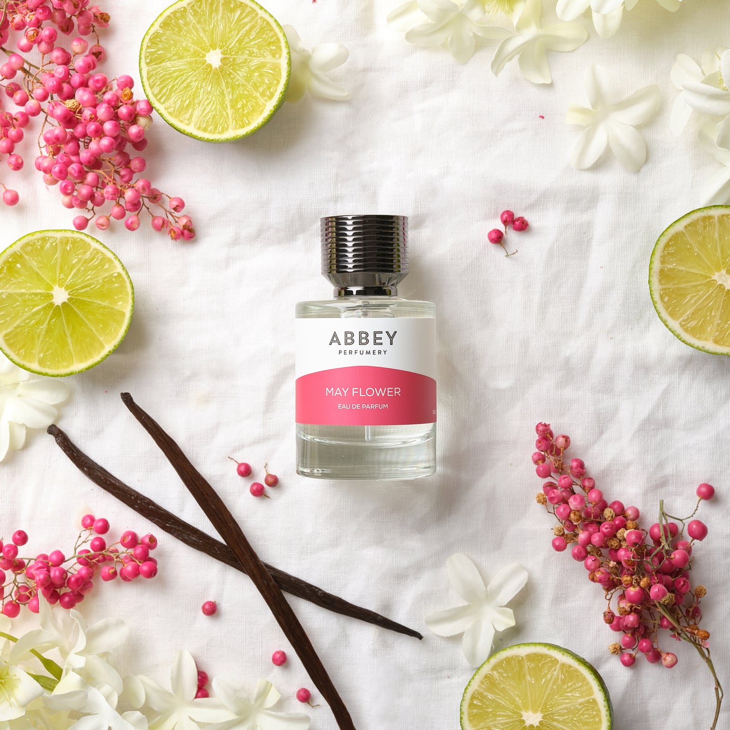 May Flower perfume bottle surrounded by vanilla, jasmine flowers and pink peppers
